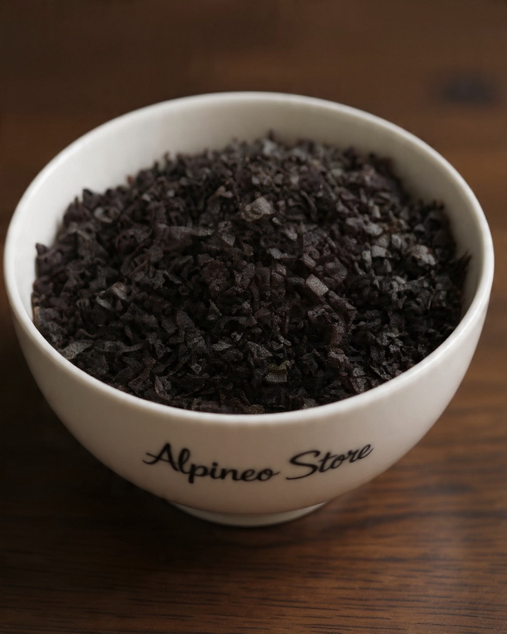 A close-up of a dark, resinous Shilajit sample in a glass dish with a wooden backdrop. Shilajit Resin — Natural Mineral Wellness
